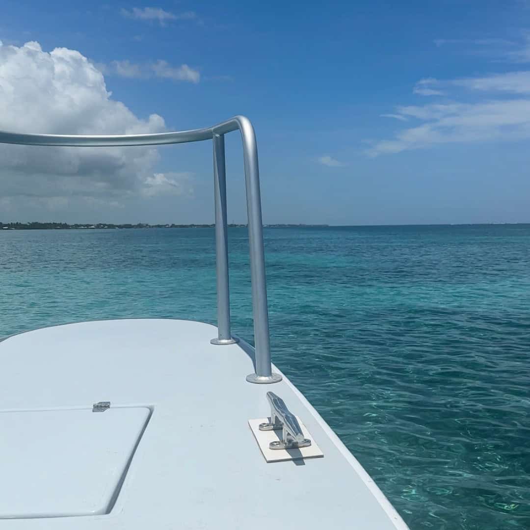 A white boat with silver railings looking over calm brightly turquoise water