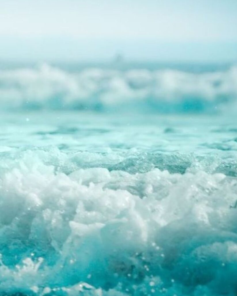 Frothy white waves crashing ashore from a turquoise ocean.