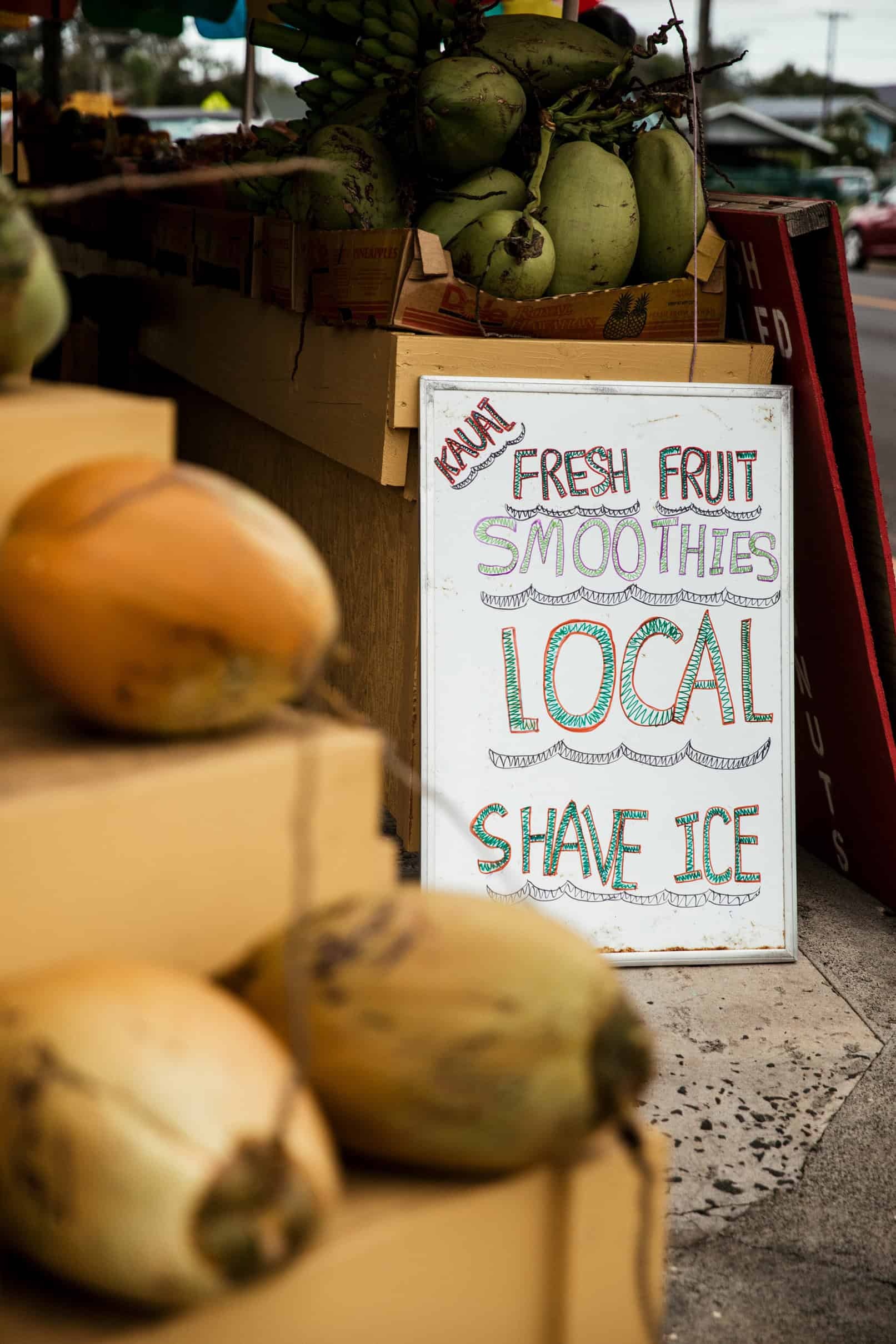 A sign at a fruit stand in Kauai that says fresh fruit, smoothies, local shave ice