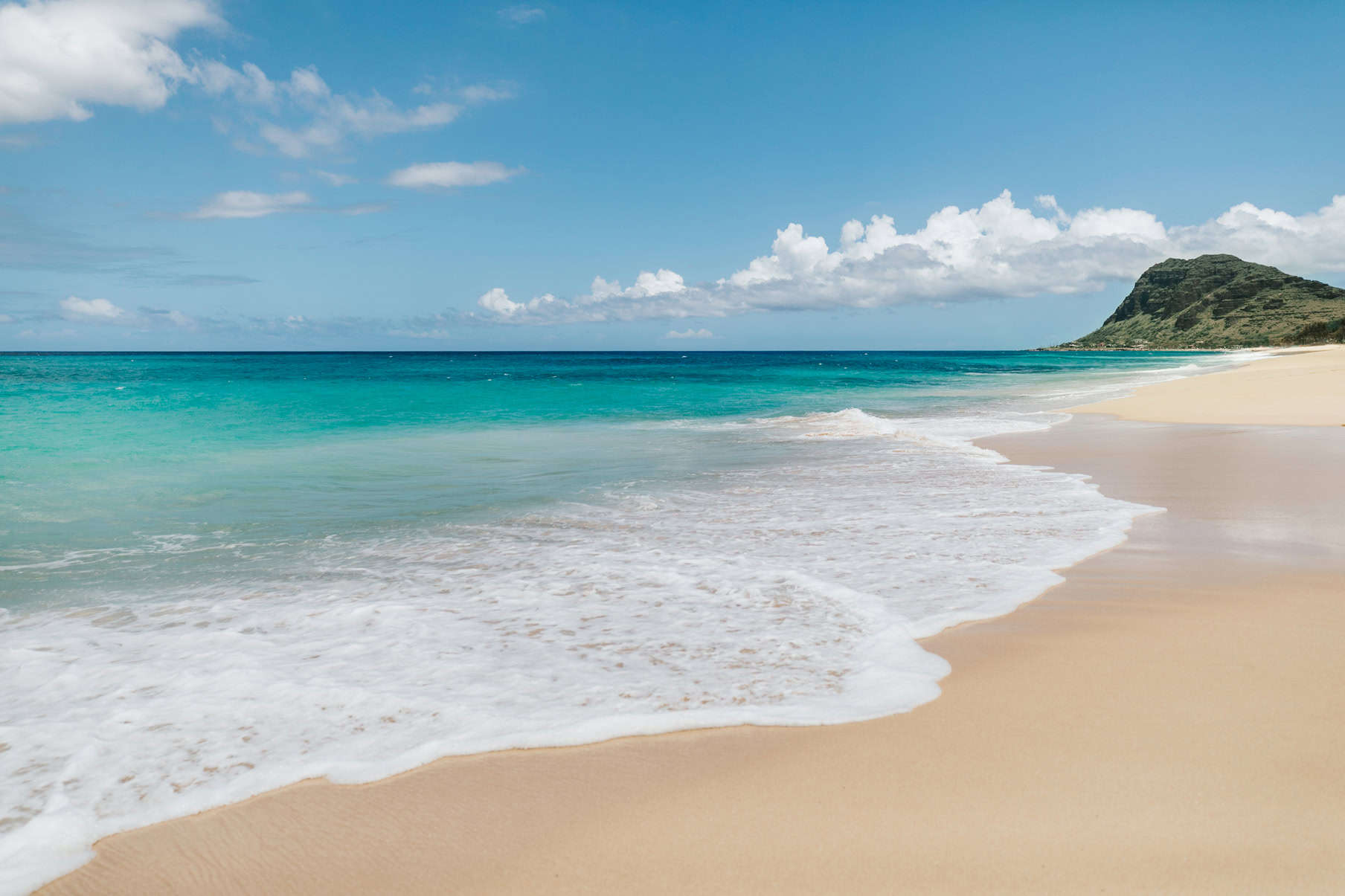 A white sand beach with a small island off to the right in the background