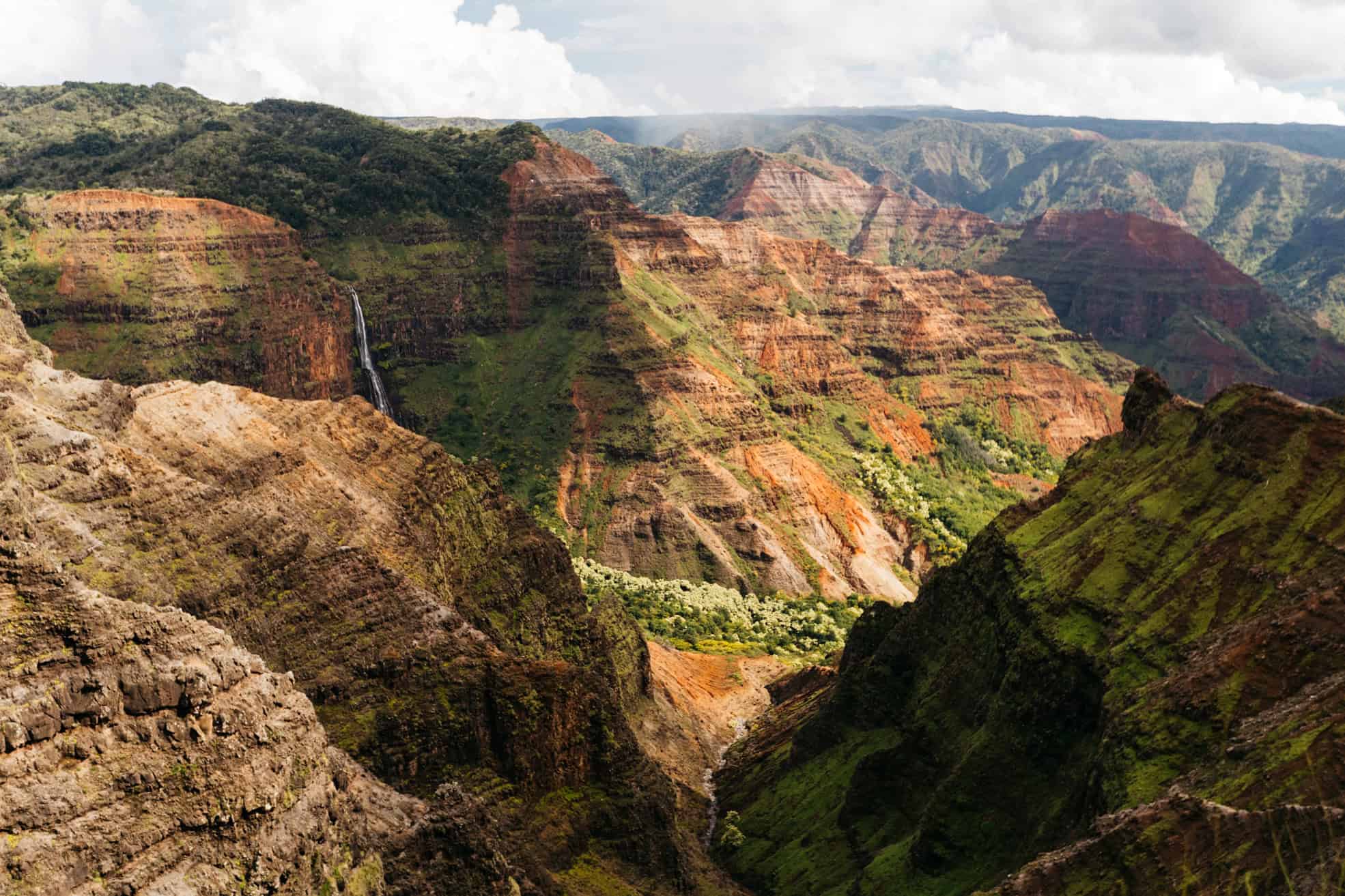 A canyon landscape in Waimea Canyon Kauai with tall red and brown rock cliffs