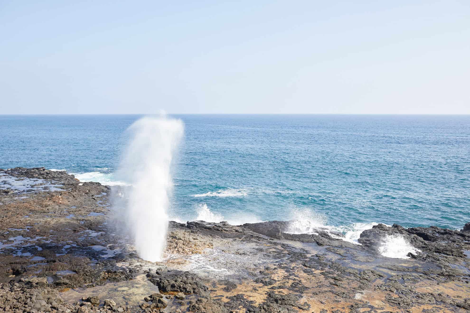 Water blowing up tall into the air out of rocks near the ocean in Kauai.