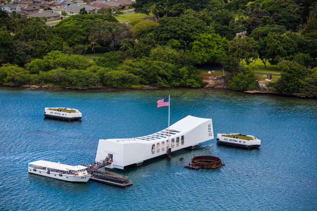 A white structure in the middle of water with an American flag on its roof and boats surrounding it