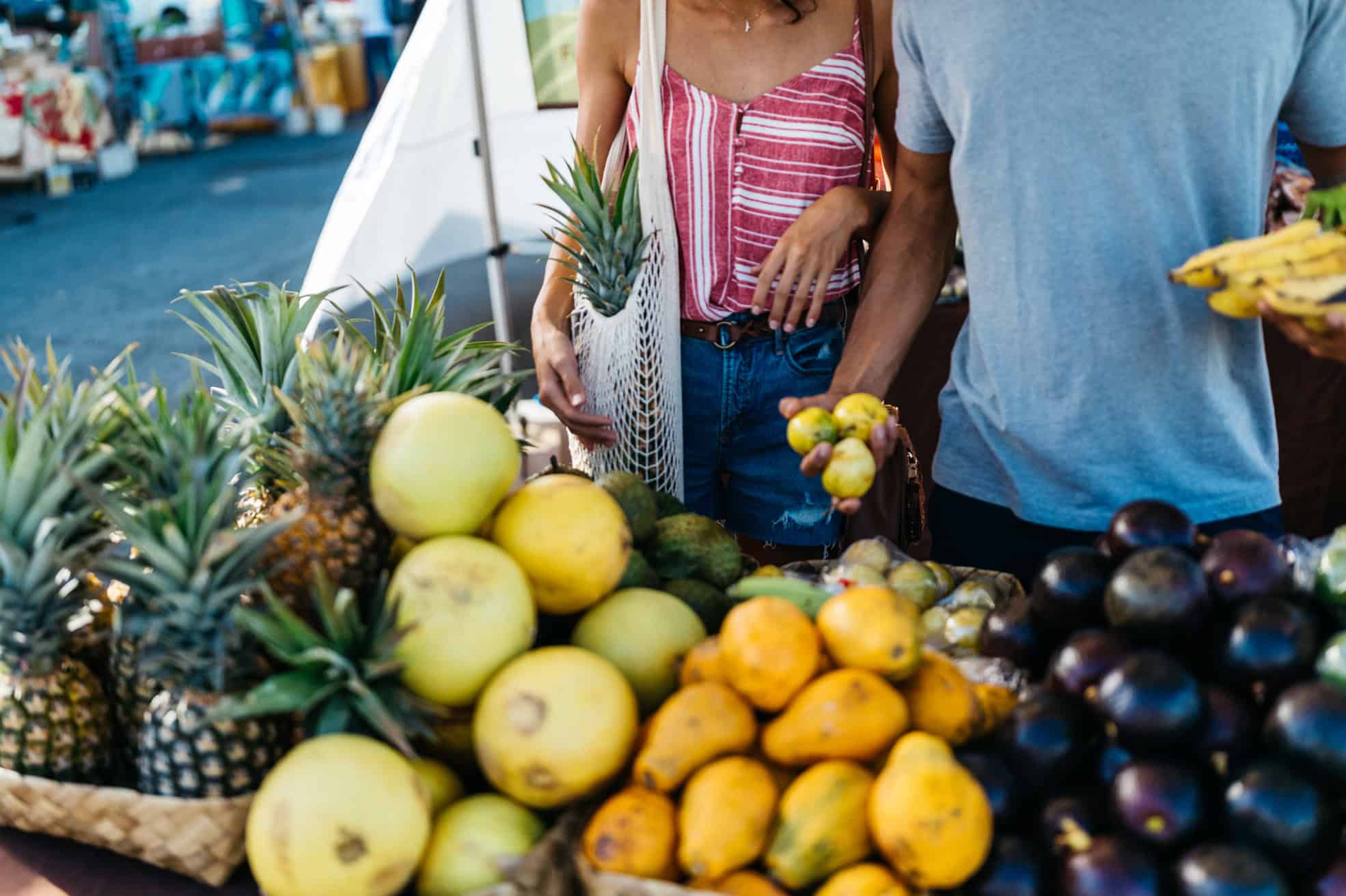 A woman and man shopping at a fruit stand with bright yellow colored fruit