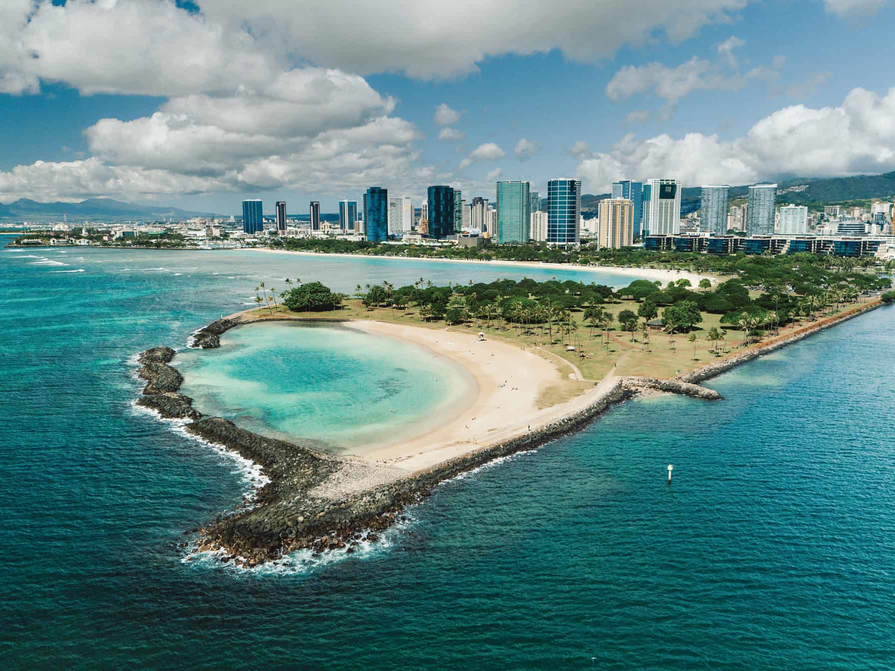 A city alongside an ocean with a manmade beach jetting into the ocean