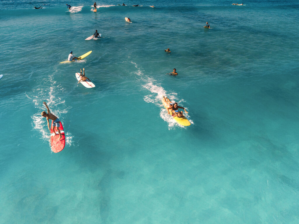 A group of surfers including children on colorful surf boards in the water