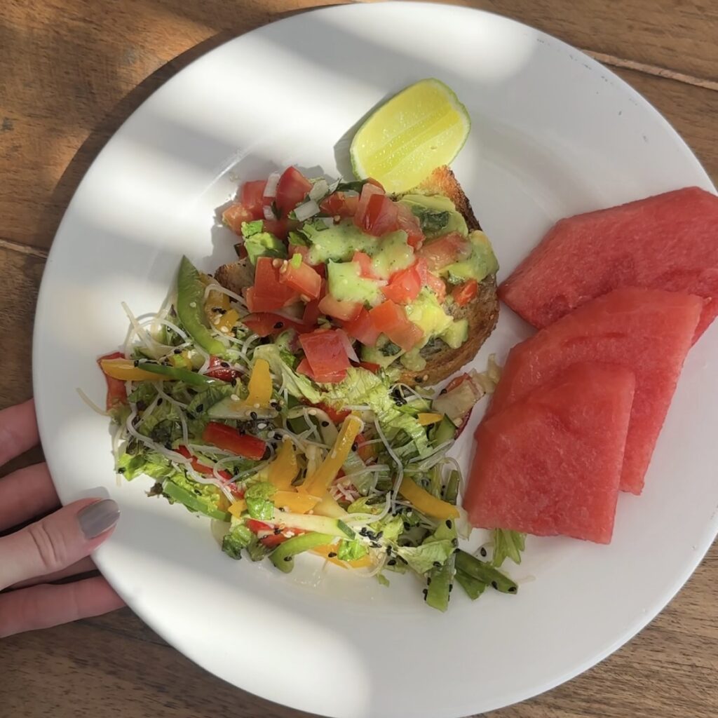 A white plate with salad, a lime and watermelon slices