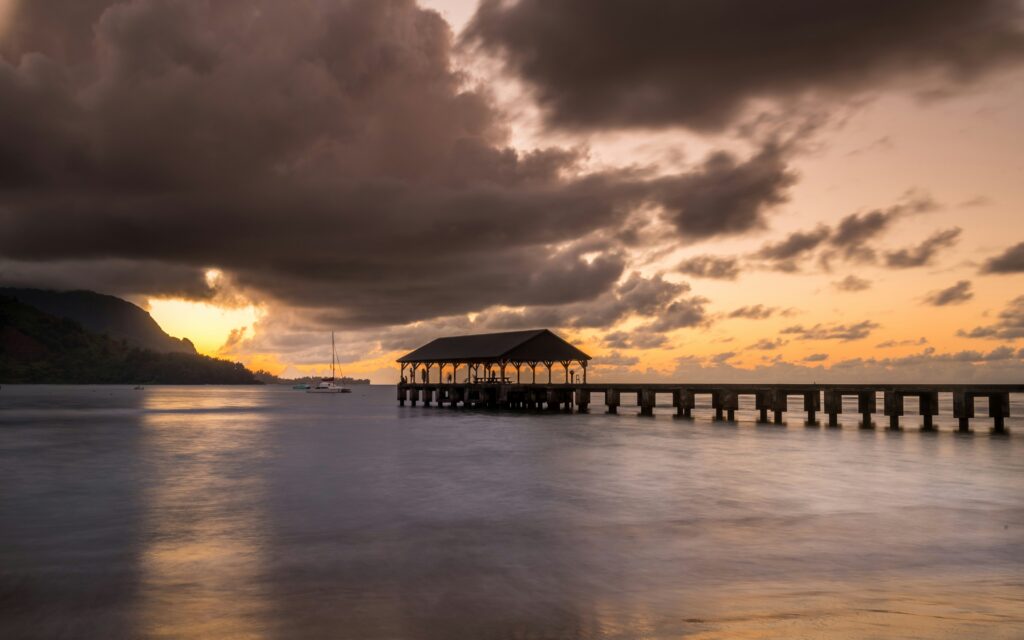 A gloomy sky over a dock with a covered end on calm waters