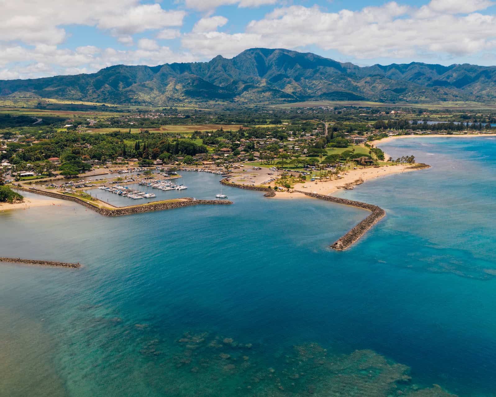 An aerial view out over the water, looking towards a town with a mountain behind it.