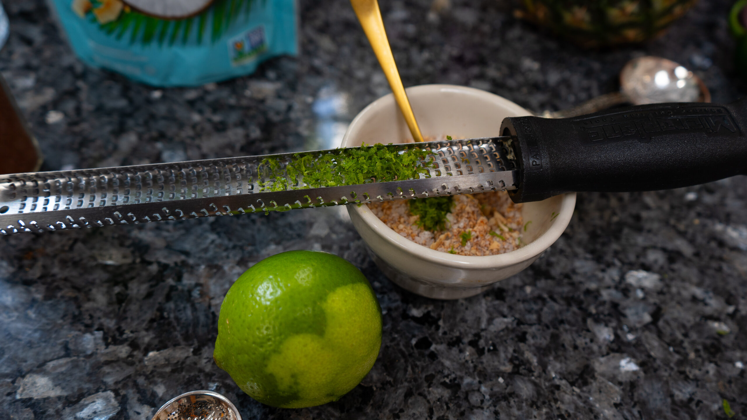 A zester next to a lime on top of a bowl