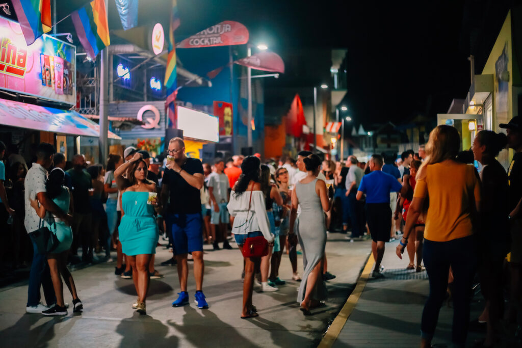 A street in Puerto Rico at night with lots of people out walking around.