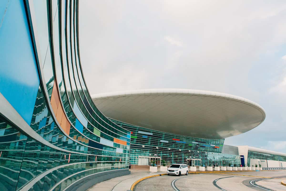 The outside of an airport with a white van in front of it.