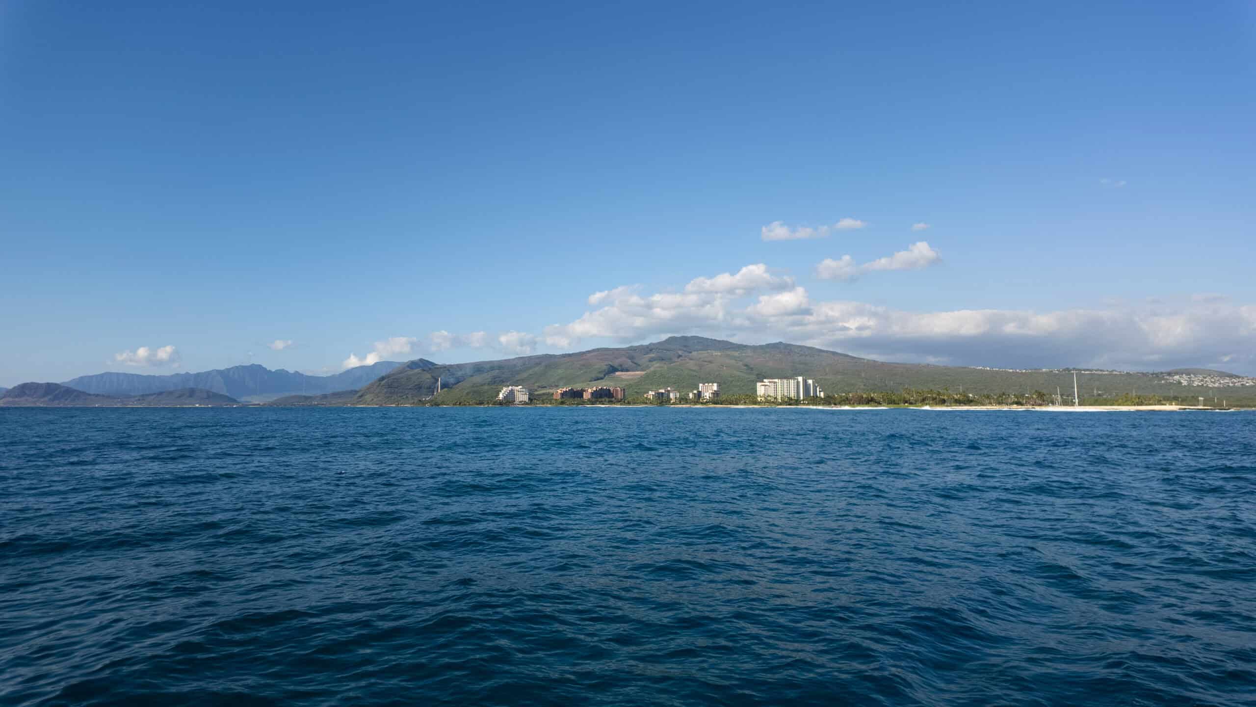 A view of an island with hotels on it from the ocean.