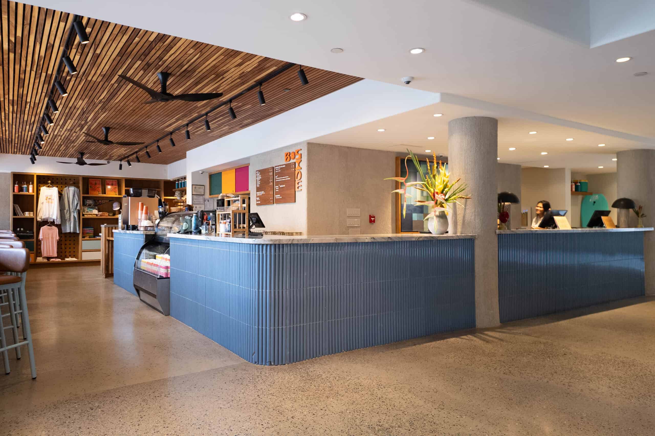 An open lobby with a blue coffee shop and reception desk